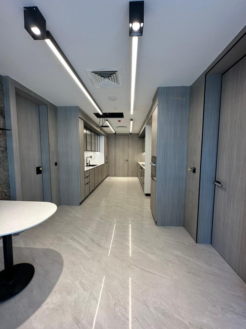 Galley kitchen at Project 39B with grey wood-grain joinery and a white solid surface worktop